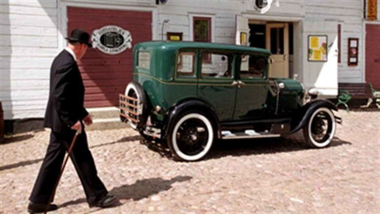 Gamla Linköping äldre grön bil och man med hatt och käpp