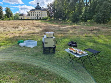 Lunchen för barnen i förskolebussen är uppdukad på campingbord och värmevagn på en gräsyta i ett natursköntområde.