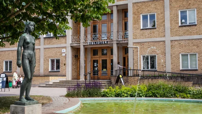 Fasaden av Ljungsbro bibliotek. I förgrunden syns fontänen och skulpturen av en naken kvinna.