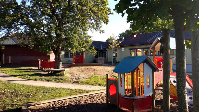 Stureforsvägens förskola och gård, med hus, sandlåda, klätterställning och fina grönskande träd