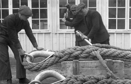 Tre män som arbetar mede slagning av grovt tågvirke