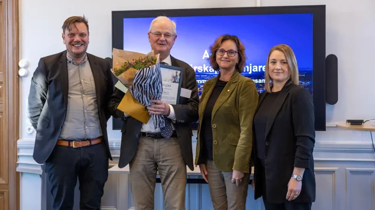 Fyra personer står på rad. Lars Holgersson står med blommor i famnen.