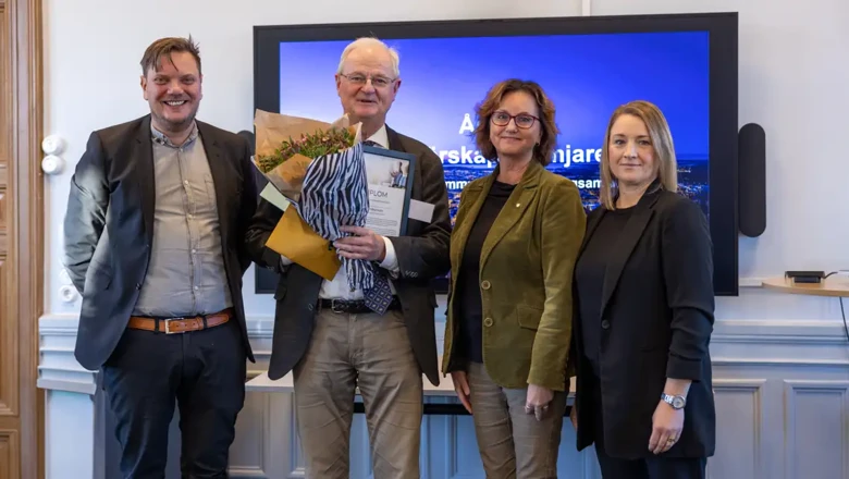 Fyra personer står på rad. Lars Holgersson står med blommor i famnen.