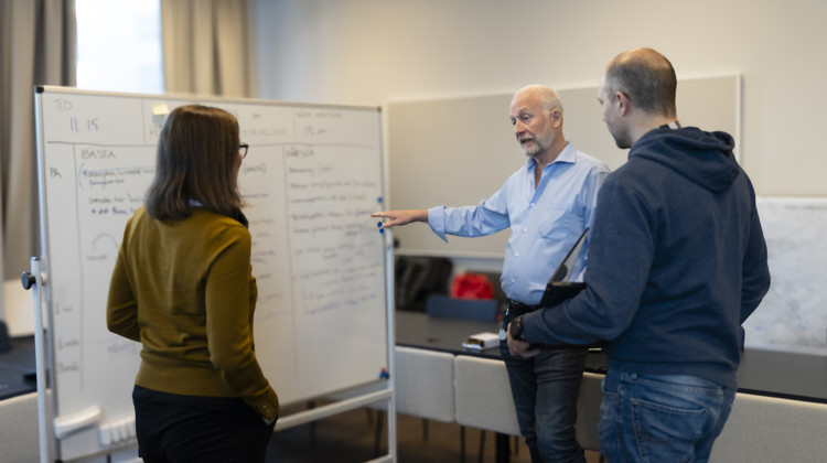 En grupp människor som står runt en whiteboardtavla.