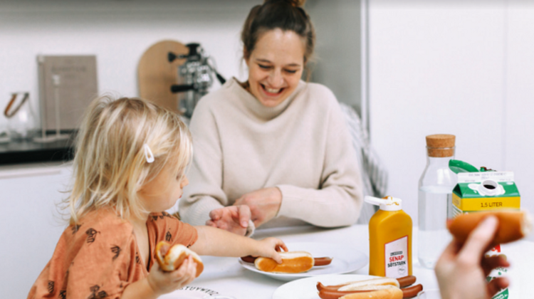 vuxen kvinna och ett barn sitter vid ett matbord.