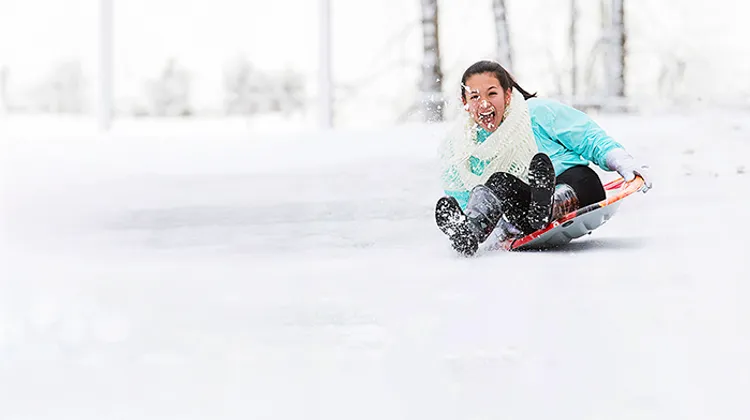 En flicka åker pulka nedför en snötäckt sluttning