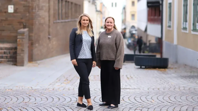 Vesna och Sara står på en kullerstensgata. I bagrunden skymtar ST Lars kyrkotorn