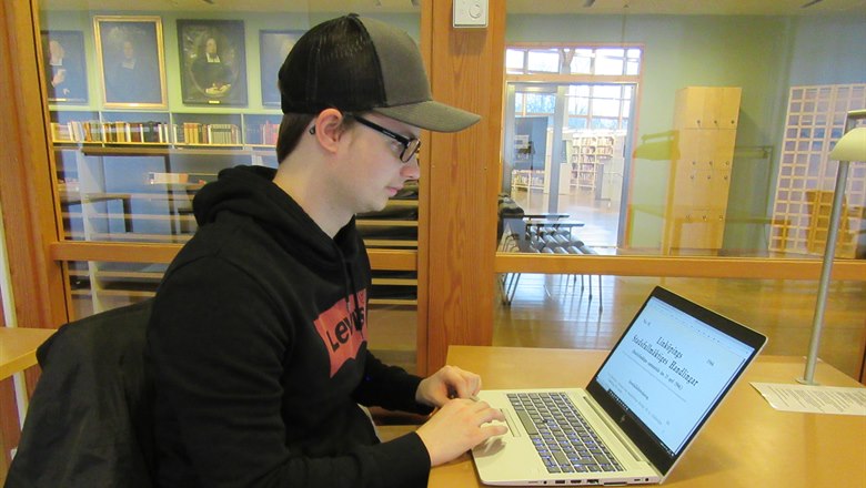 Student vid skrivbord söker via laptop i stadsfullmäktigeprotokoll